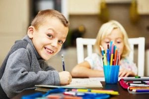 young boy working on homework with a smile