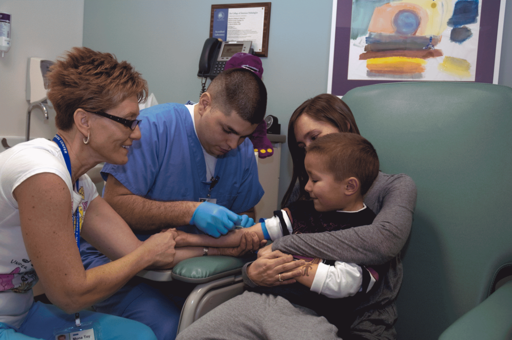 Dayton Children's Hospital Lab staff helping a young boy draw labs